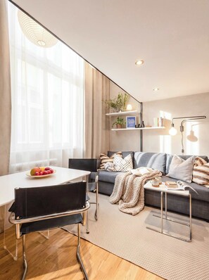 A modern living room with a sofa, a dining table with chairs, and a coffee table.