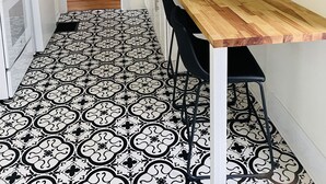 A compact kitchen with white cabinets, a wooden countertop, and a black and white patterned floor. - Large One Bedroom Downstairs - with laundry (Medina)