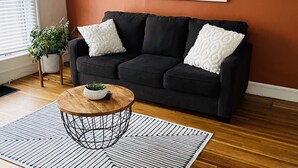 A living room with a dark sofa, a round coffee table, and a patterned rug. - Large One Bedroom Downstairs - with laundry (Medina)