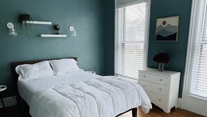 A bedroom with a bed, nightstands, a dresser, a rug, and a window with blinds. - Large One Bedroom Downstairs - with laundry (Medina)