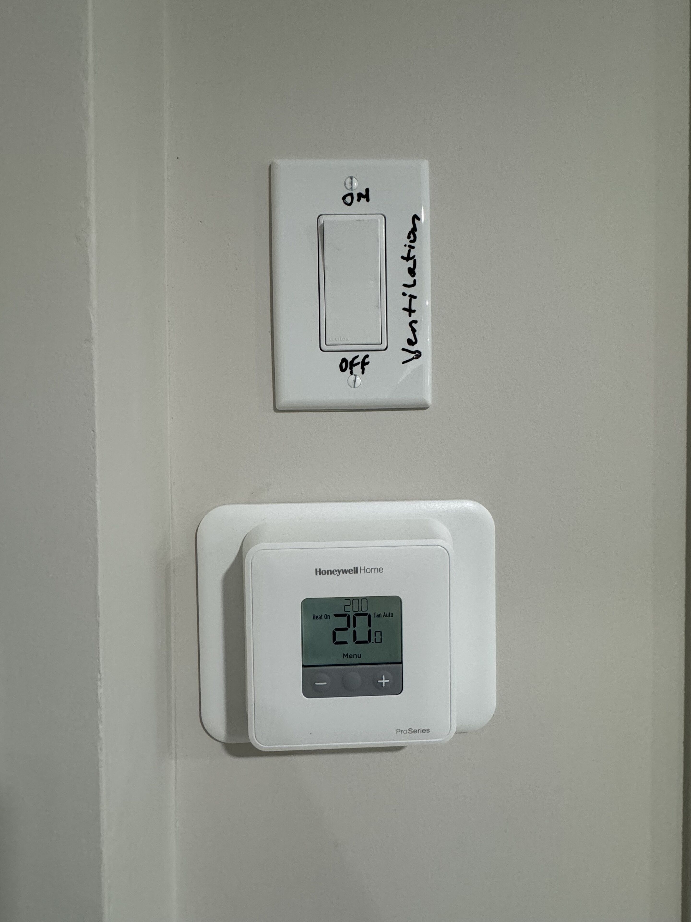 En termostat och en ventilationsströmbrytare på en vägg.