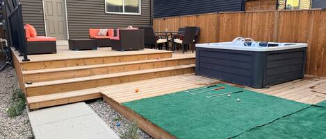A backyard with a hot tub, outdoor seating, and a small pool.