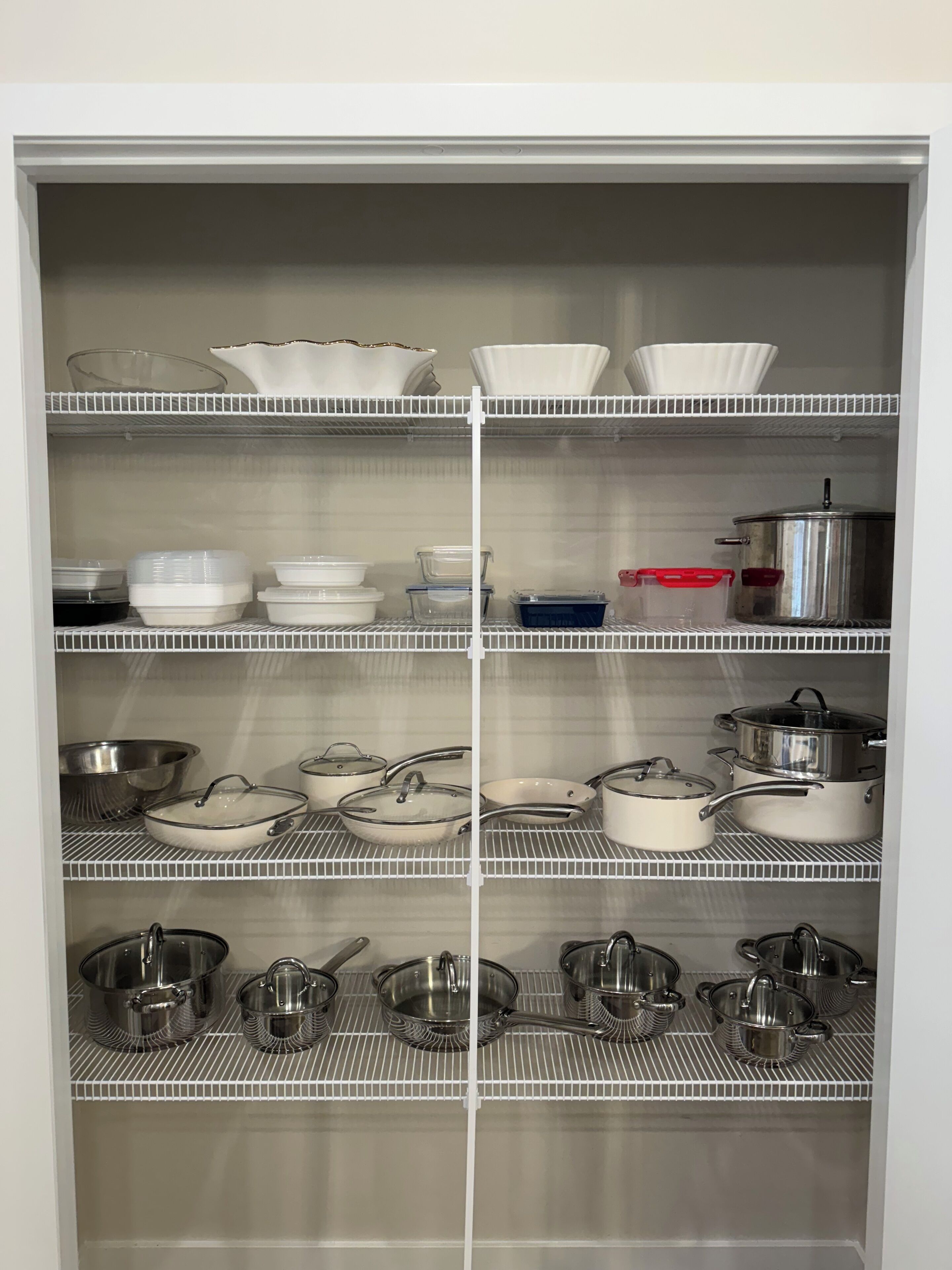 Une cuisine avec des étagères blanches où sont rangés divers ustensiles, notamment des bols, des assiettes et des casseroles.