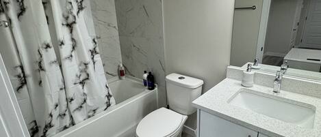 Een moderne badkamer met een bad, toilet en wastafel.