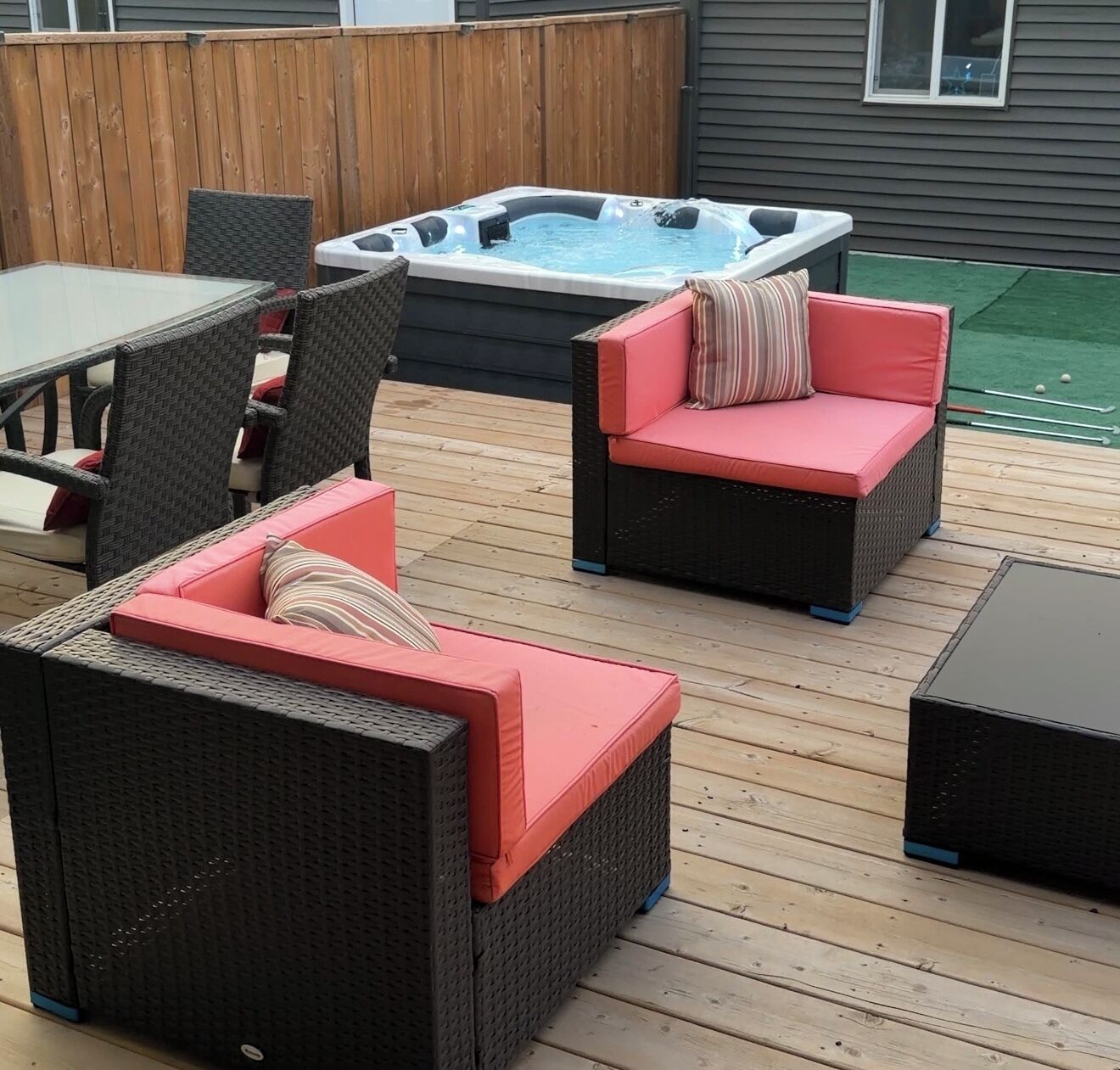 An outdoor deck with wicker furniture, a hot tub, and a wooden deck.