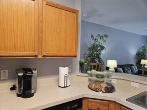 A kitchen with wooden cabinets, a coffee maker, a paper towel dispenser, and a decorative glass bowl on the counter. - 5BR Ocean-Themed Villa w/Private Pool Near Disney (Davenport)