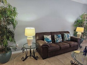 A living room with a brown leather sofa, two lamps, and decorative pillows. There are two potted plants, one on each side of the sofa. - 5BR Ocean-Themed Villa w/Private Pool Near Disney (Davenport)
