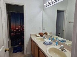 A bathroom with two sinks, a large mirror, and a shower curtain with a cityscape design. - Discovering Nemo and Dori Paradise! 2 min to Posner Park (Davenport)