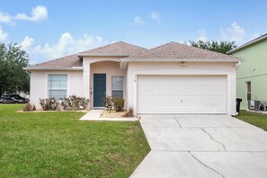 A single-story house with a garage, a front door, and a small front yard.