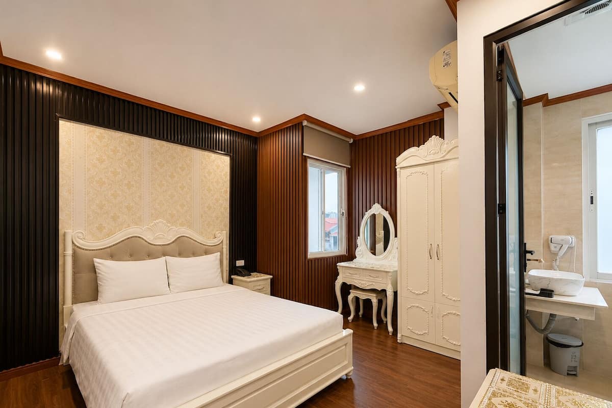 A bedroom with a large bed, a vanity with a mirror, and a wardrobe.
