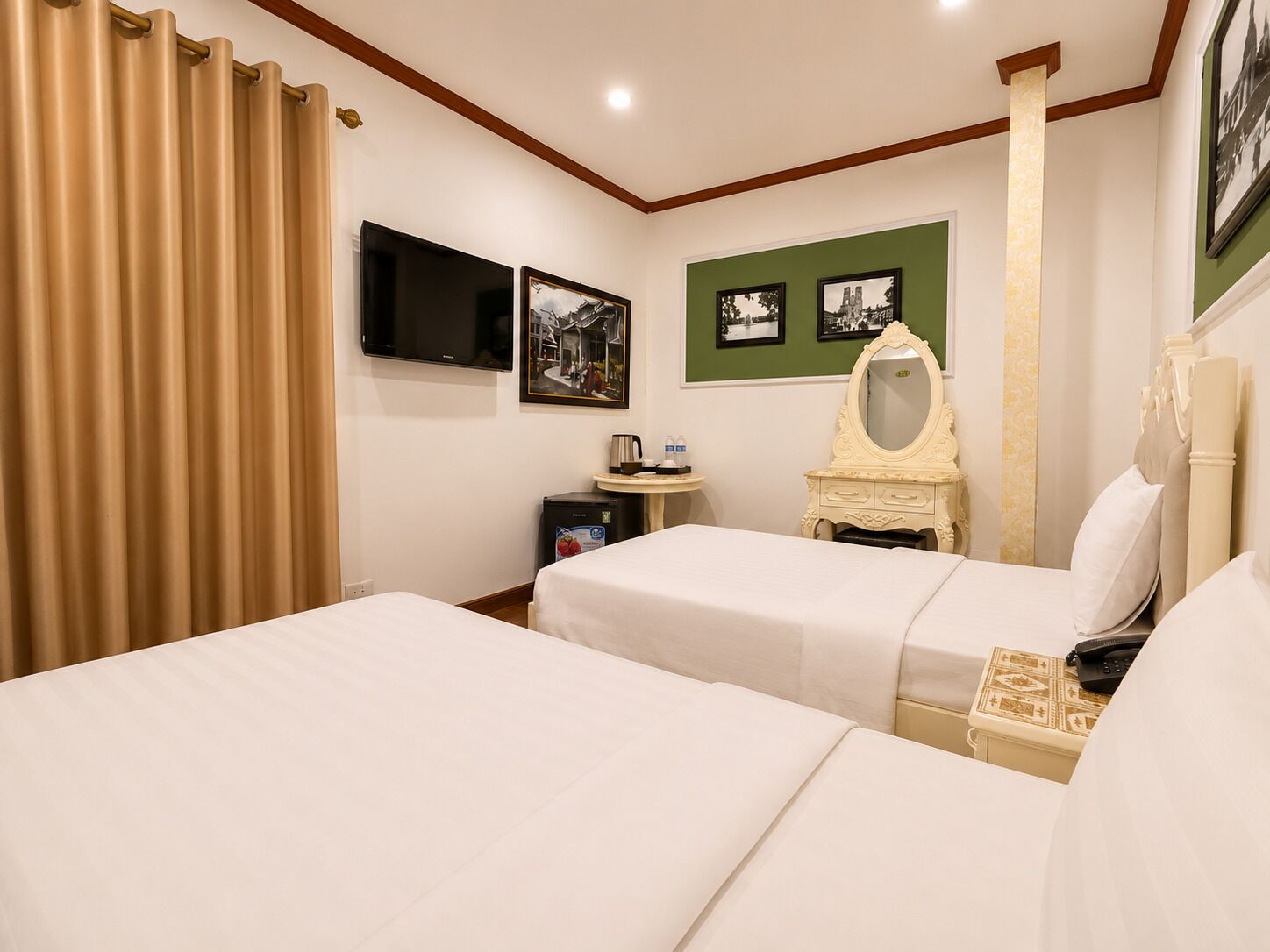 A hotel room with two beds, a television, a small table with a lamp, and a mirror.