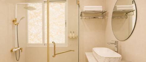A modern bathroom with a glass-enclosed shower, a marble sink, a towel rack, and a mirror.