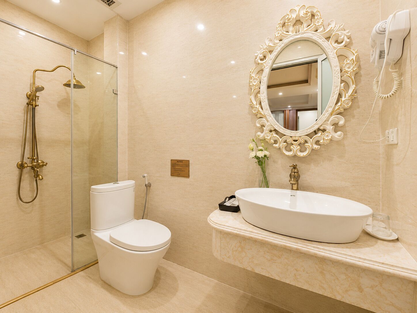 Ein Badezimmer mit Duschkabine, Toilette, Waschbecken mit Spiegel und einem an der Wand montierten Fön.