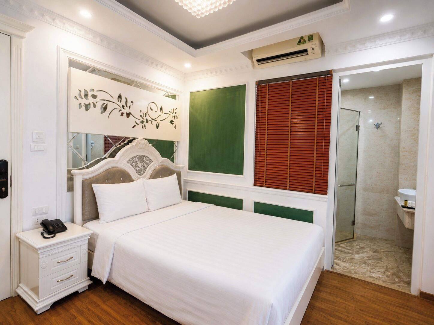 A bedroom with a bed, bedside table, and a shower area.