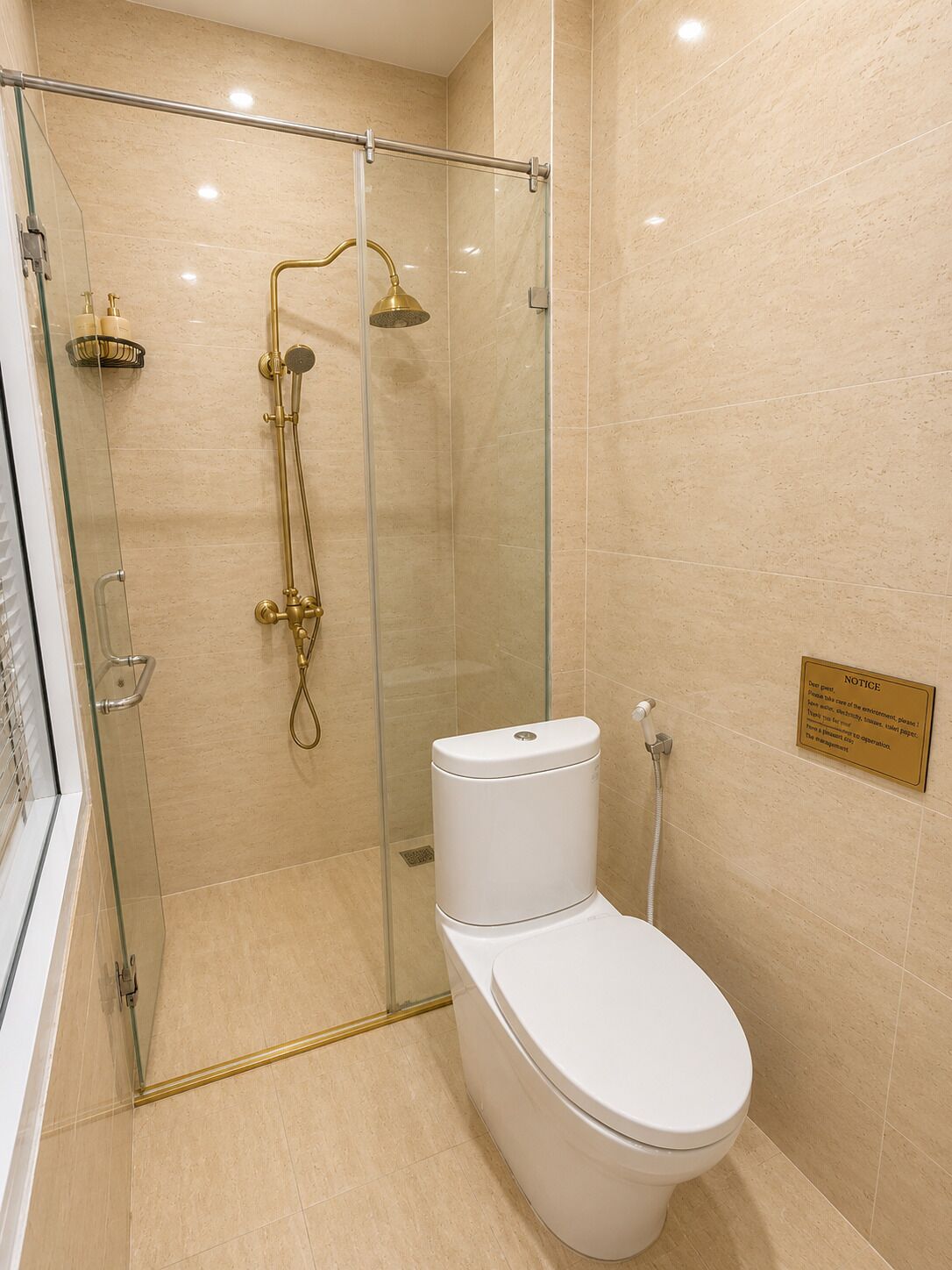 A modern bathroom with a glass-enclosed shower, a white toilet, and a notice board on the wall.