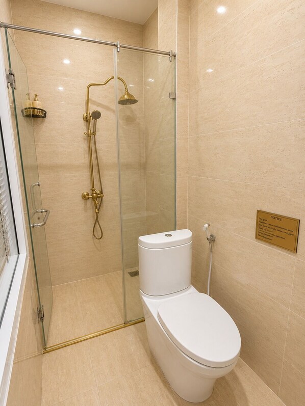 Un baño moderno con ducha de vidrio, inodoro blanco y un tablón de anuncios en la pared.