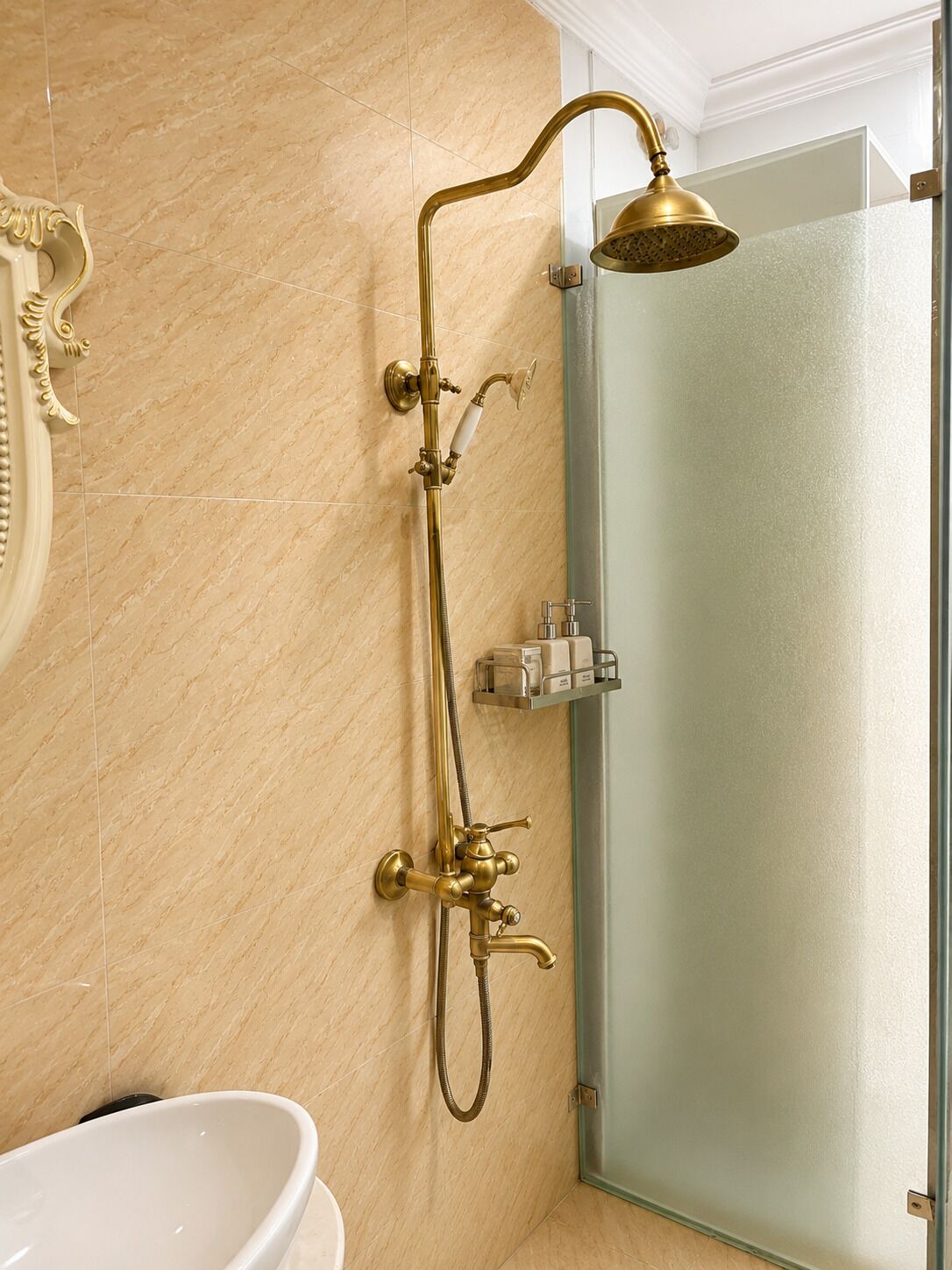 Un baño con ducha dorada, bañera blanca y cabina de ducha de vidrio.