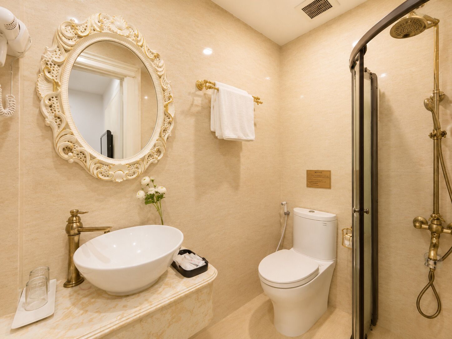 A bathroom with a large ornate mirror, a sink, a toilet, and a shower.