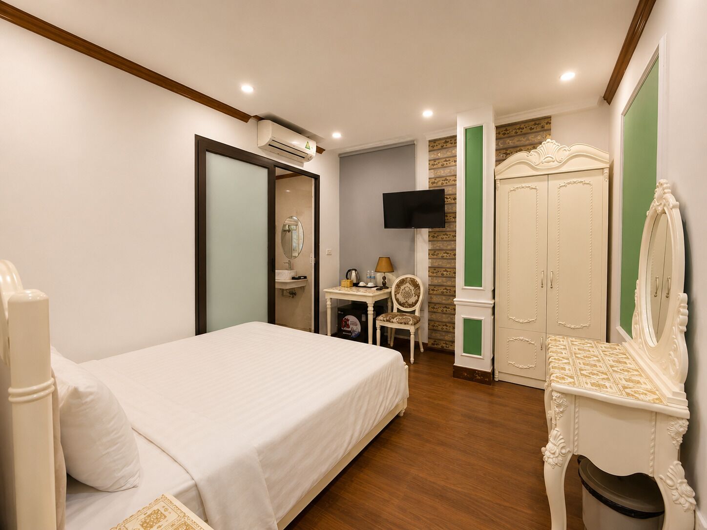 Una habitación de hotel con cama, escritorio, silla, armario y televisión.