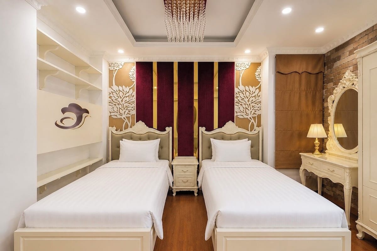 A double bed room with a chandelier, a mirror, and a vanity with a lamp.