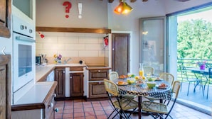 Una cocina con salpicadero de azulejos, armarios de madera, una mesa de comedor con sillas y vistas al exterior.