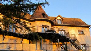 Un edificio grande con una torre destacada, un balcón y una escalera que lleva al piso superior.