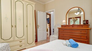 Un dormitorio con cama, cómoda, espejo y puerta que da a otra habitación.