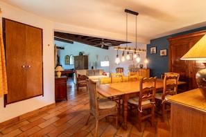 A dining area with a wooden table and chairs, a ceiling fan, and hanging light fixtures.