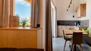 Eine moderne Küche mit Holzausstattung, ein Essbereich mit Tisch und Stühlen sowie ein Ausblick durch ein Fenster.