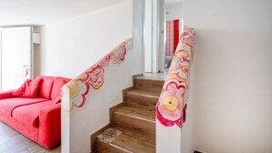 Uma escadaria com degraus de madeira e um sofá vermelho em primeiro plano.