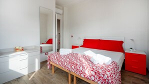 Quarto com cama, mesas de cabeceira, espelho, banco e guarda-roupa.