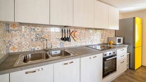 Eine moderne Küche mit gefliestem Fliesenspiegel, Spüle aus Edelstahl, Mikrowelle, Backofen und einem gelben Kühlschrank.
