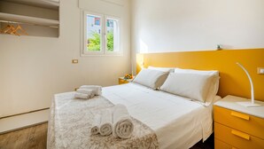 Ein Hotelzimmer mit Bett, Nachttisch, Fenster und einer Wandregal.