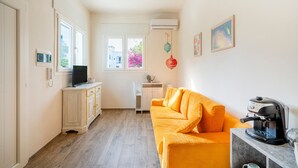 Ein gemütlicher Wohnraum mit einer Couch, einer Kaffeemaschine, einem Fernseher und einem kleinen Tisch.
