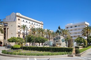 Une place publique avec une fontaine, des palmiers et une statue.