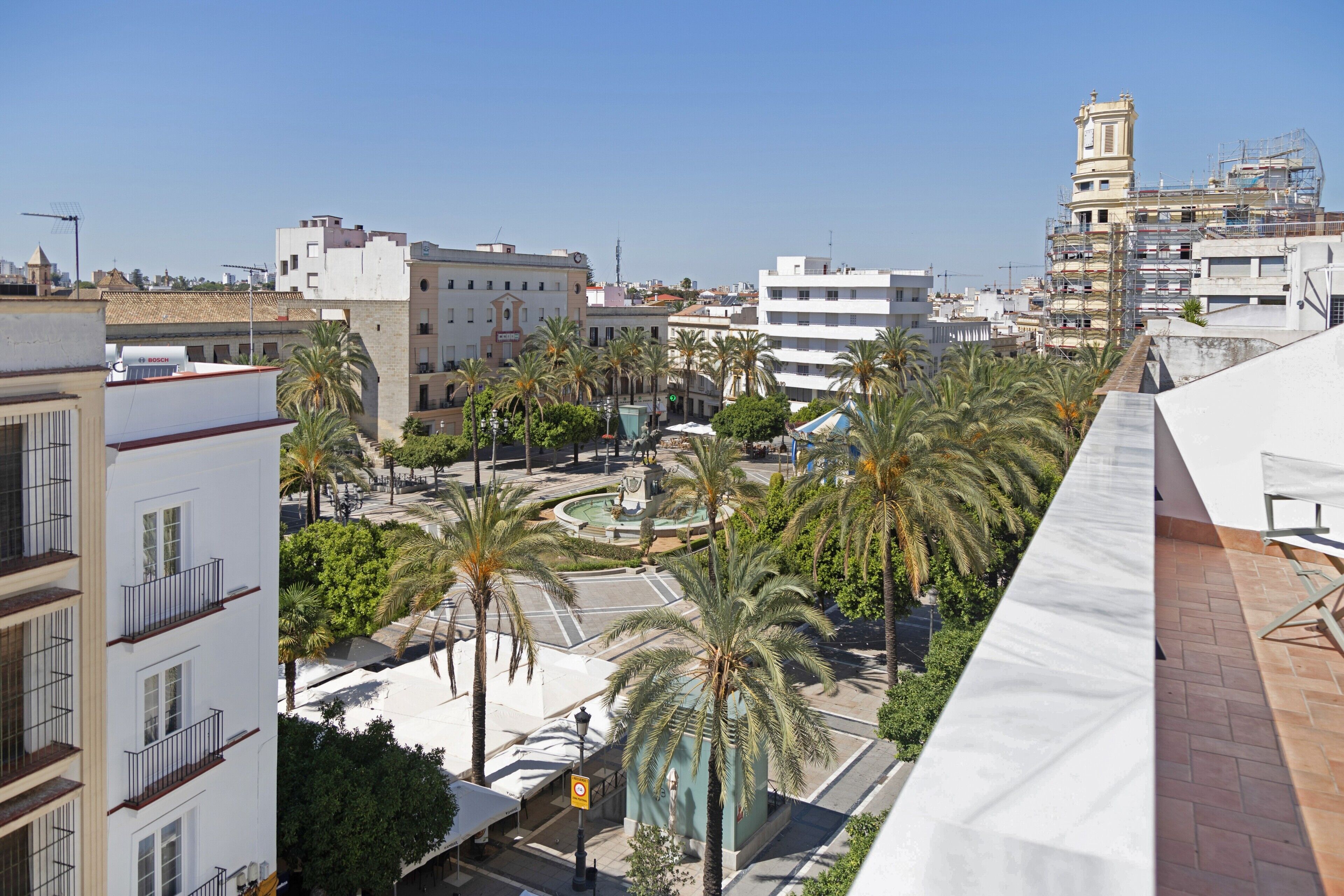 Un paysage urbain avec des immeubles, des palmiers et un rond-point.