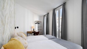 Une chambre d’hôtel avec un lit, un bureau, une chaise et une fenêtre avec des rideaux.