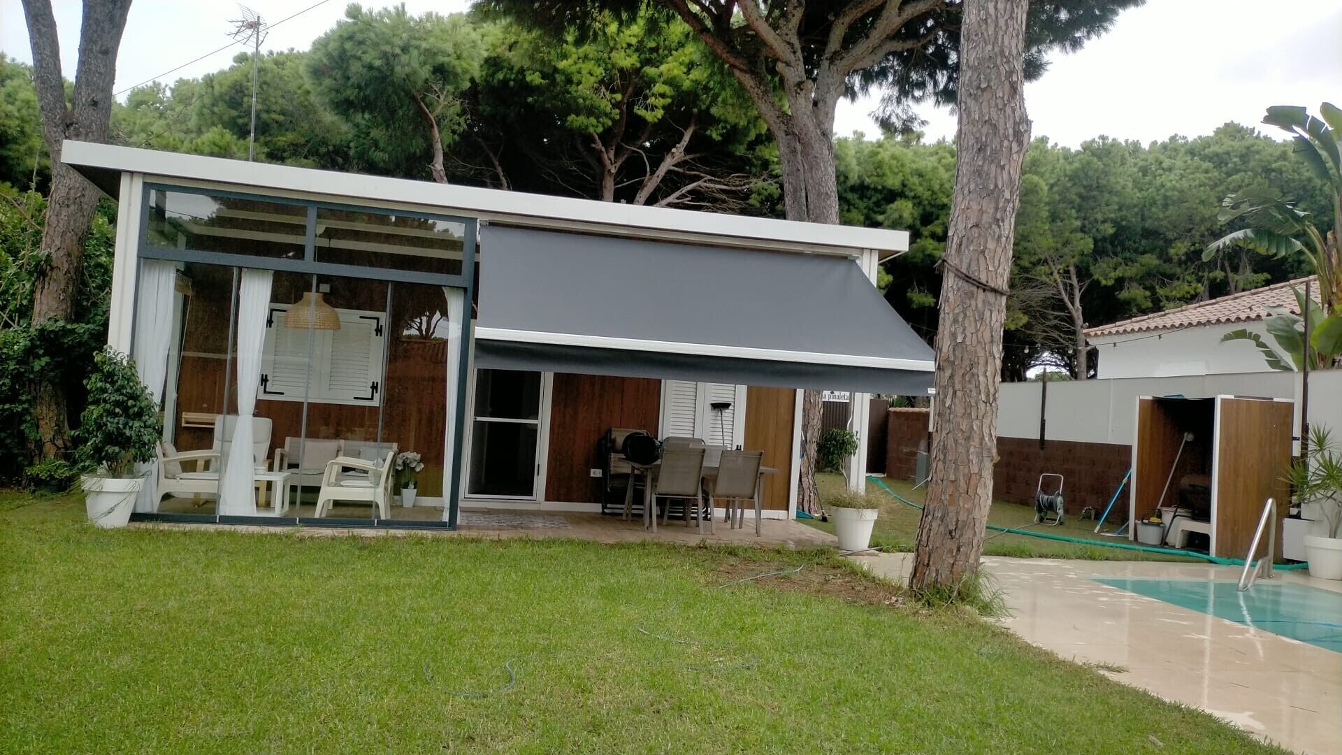 Et moderne hus med en overdækket terrasse, swimmingpool og have.