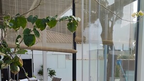 Een glazen patio met buitenmeubilair, een zwembad en uitzicht op de omgeving.