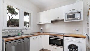 Een kleine keuken met een vaatwasser, oven, magnetron en een wasmachine.