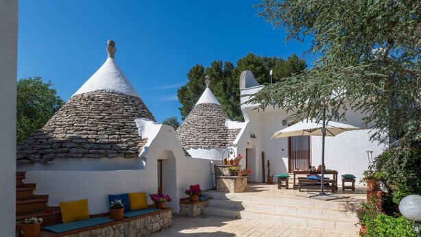 A courtyard with stone-roofed buildings, outdoor seating, and potted plants. - Villa 'Trulletti Gioia' with Private Pool, Wi-Fi and Air Conditioning (Ceglie Messapica)