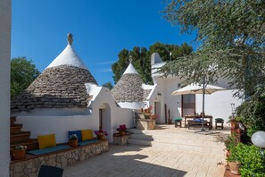 Un patio con edificios de techo de piedra, mobiliario al aire libre y plantas en macetas.