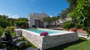 A pool with stone walls, surrounded by greenery and a white building with a conical roof. - Villa 'Trulletti Gioia' with Private Pool, Wi-Fi and Air Conditioning (Ceglie Messapica)