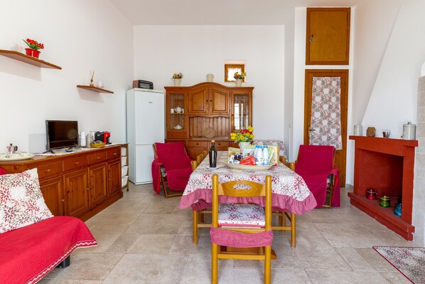 Un comedor con una mesa dispuesta para dos personas, un armario de madera, un televisor y una silla roja.