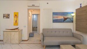 A living room with a sofa, a cabinet, and a painting of a boat.