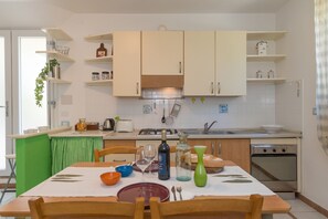 Une cuisine avec des meubles blancs, une nappe verte et une table à manger dressée avec des assiettes, des bols et des couverts.