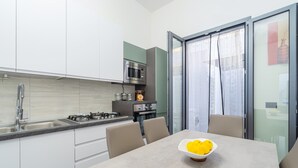 A modern kitchen with a gas stove, stainless steel appliances, and a dining area with a table and chairs. - Apartment "Erre House" with Private Terrace & Wi-Fi (Avola)