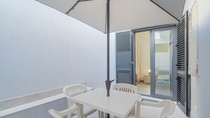 A balcony with a white table and chairs, a ceiling fan, and a sliding glass door leading to a room. - Apartment "Erre House" with Private Terrace & Wi-Fi (Avola)