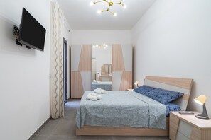 A modern bedroom with a bed, bedside table, lamp, and a TV mounted on the wall.