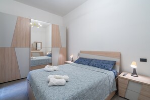Ein modernes Schlafzimmer mit Bett, Nachttischen, einem Spiegel und einer Lampe.